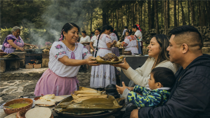 Cocinera tradicional mexiquense entrega un platillo a una familia durante una muestra gastronómica al aire libre en La Marquesa.