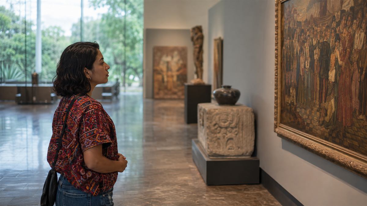 Visitante observa una exposición en una sala de museo con iluminación suave